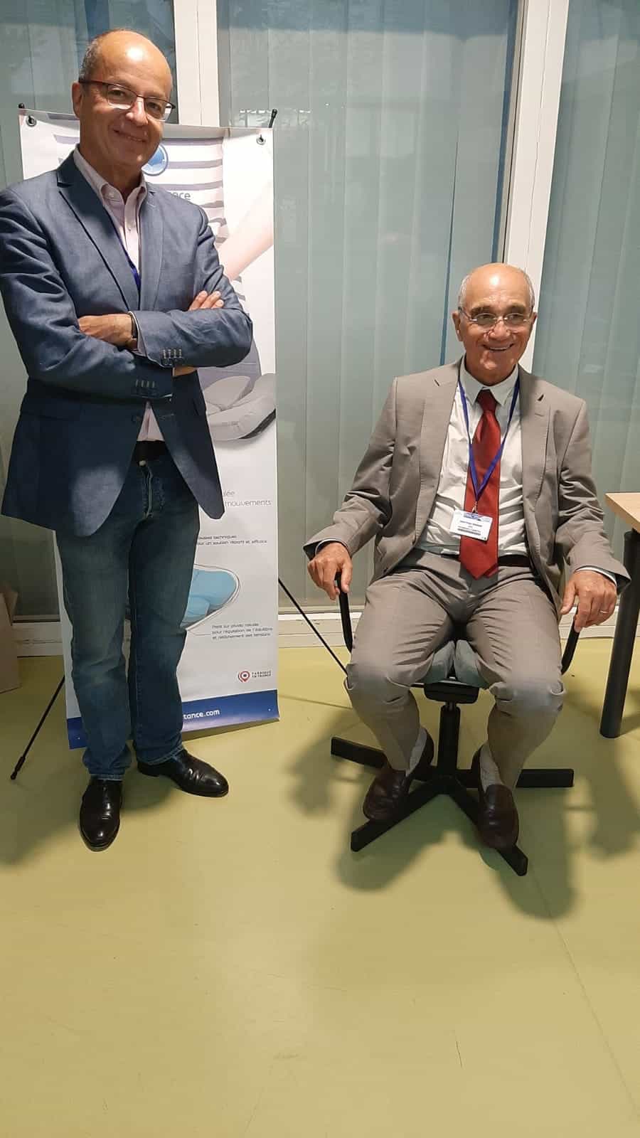 Dr. Jean-Yves Maigne sitzt auf einem Sessel mit Aporia-Sitzfläche; Pascal Azadian steht neben dem Blue-Portance-Banner.